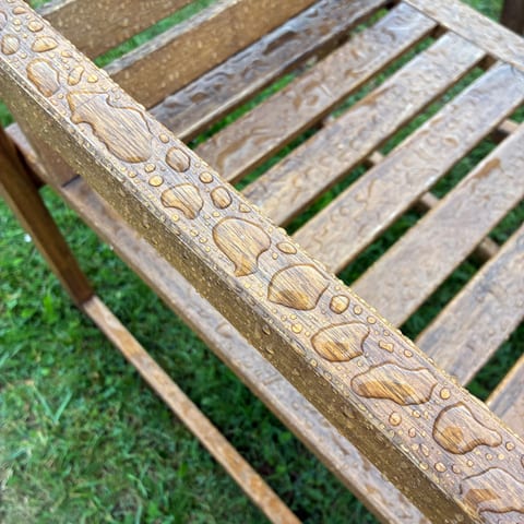 Rainwater beading on the arm and slats of an Ikea NÄMMARÖ acacia garden chair treated with Osmo UV-Protection-Oil Extra
